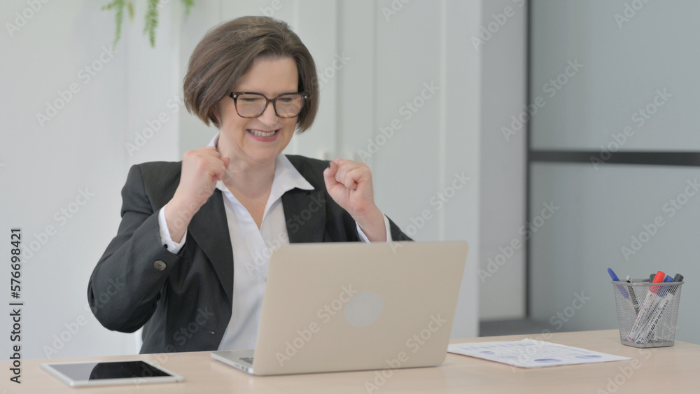 Old Businesswoman Celebrating Online Success on Laptop in Office Old Businesswoman Celebrating Online Success on Laptop in Office