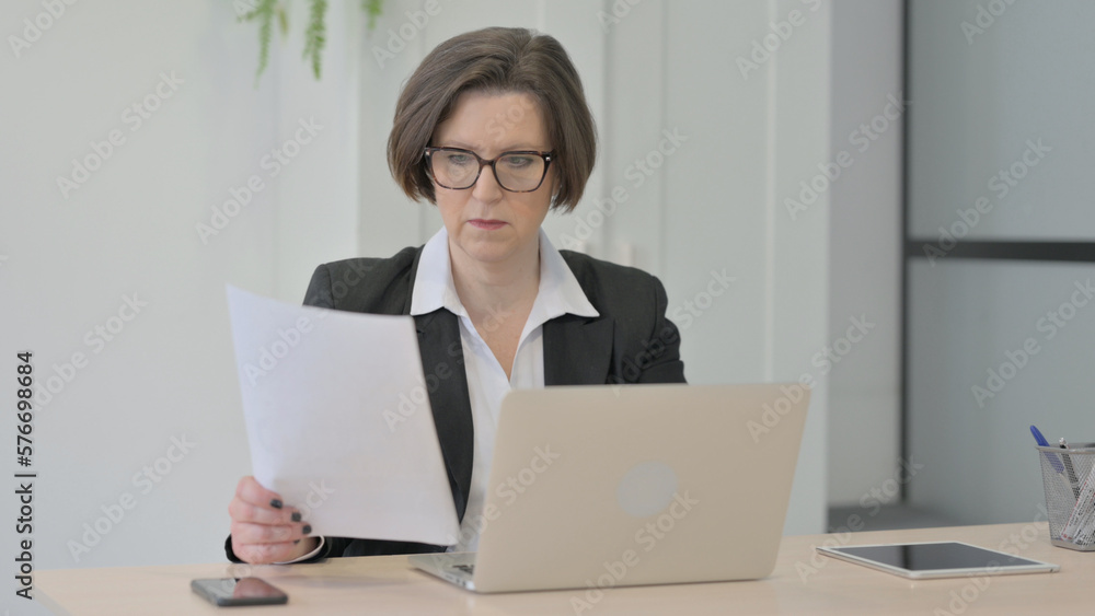 Old Businesswoman Working on Laptop and Documents Old Businesswoman Working on Laptop and Documents