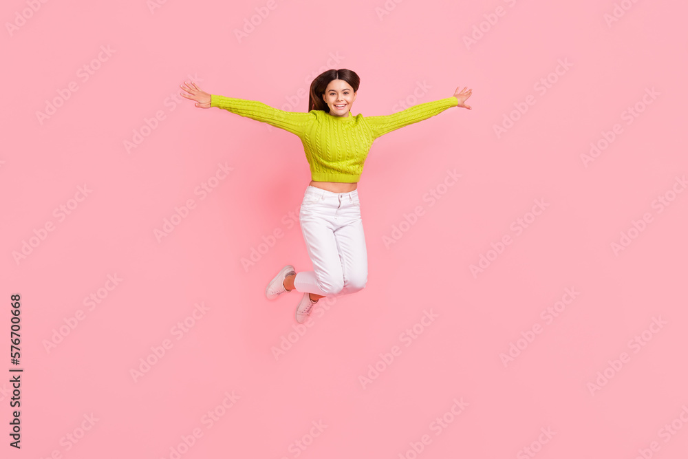 Full body photo of lovely teen lady jump spread arms flight bird playful dressed stylish green clothes isolated on pink color background Full body photo of lovely teen lady jump spread arms flight bird playful dressed stylish green clothes isolated on pink color background