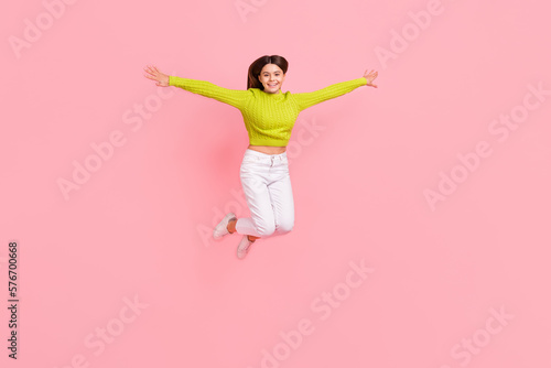 Full body photo of lovely teen lady jump spread arms flight bird playful dressed stylish green clothes isolated on pink color background