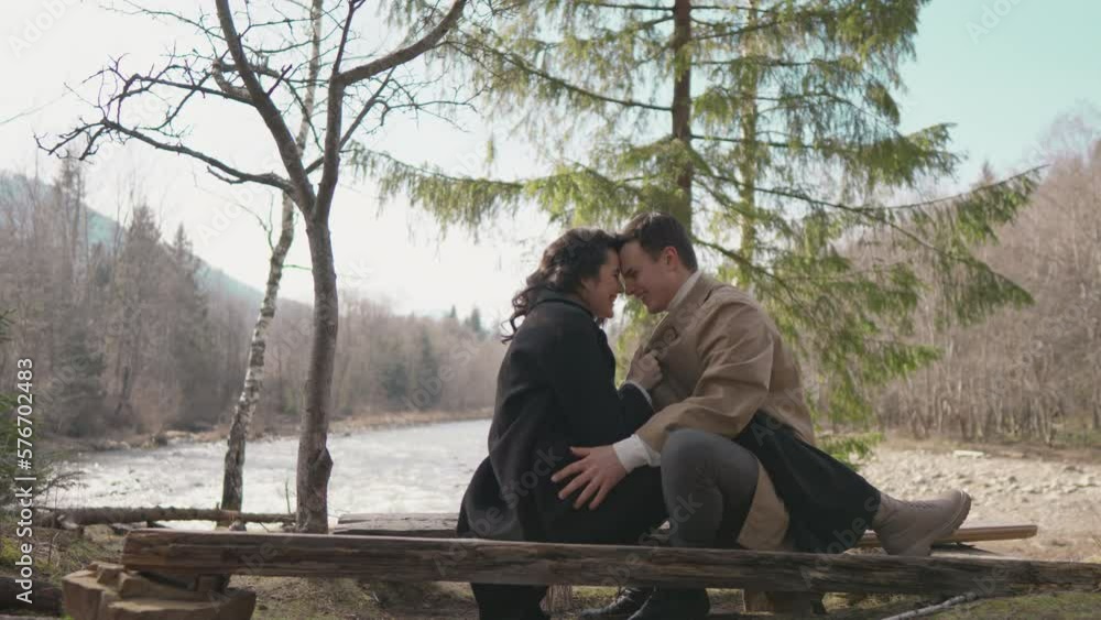 Joyful young couple flirt near river in park. Girl and boy resting in nature. Happy man woman in forest having fun, spending time together. Concept relationship, love, dating in spring, summer, autumn