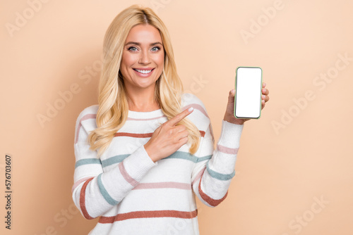 Portrait of lovely nice girl wavy hair wear striped pullover directing at phone demonstrate screen isolated on pastel color background