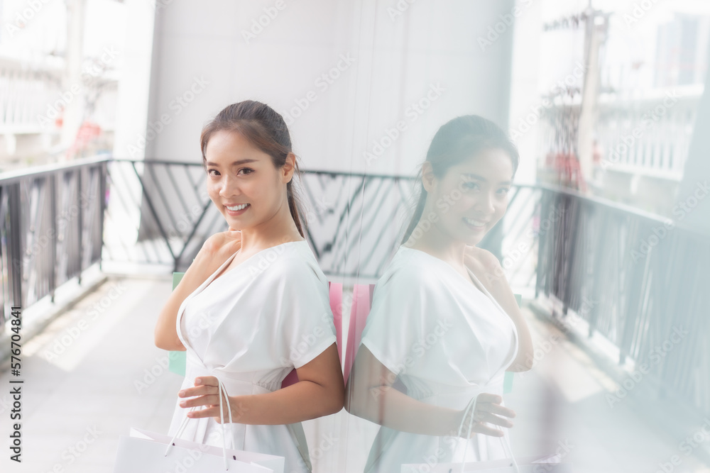 Portrait of happy smiling woman with shopping bags in corridor walk way. Beautiful woman with a paper bag.
