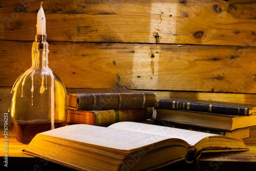 composition with old books and candlestick made with a bottle of whiskey on a wooden background