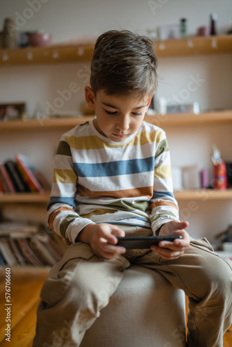One caucasian boy child use smartphone mobile phone at home play games