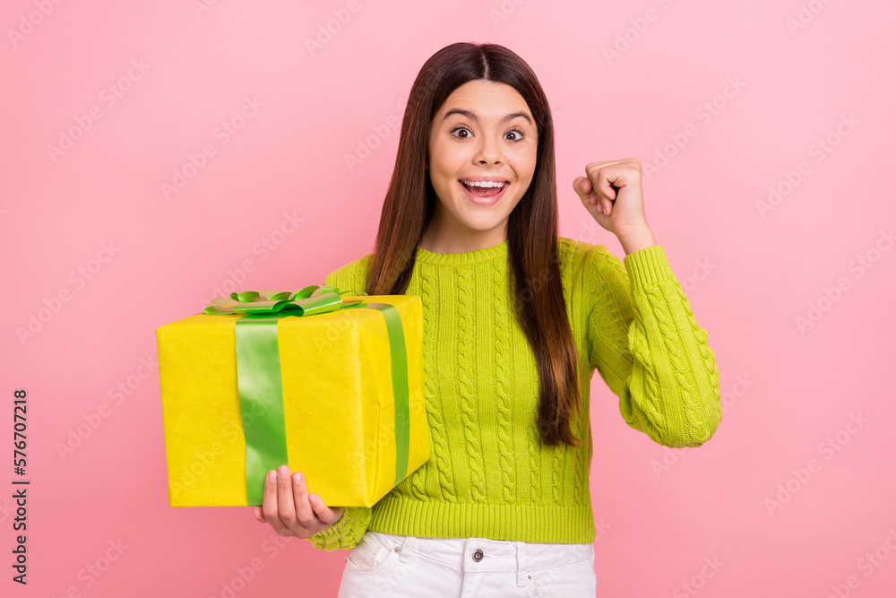 Photo portrait of lovely teen lady raise fists excited receive large giftbox wear trendy green garment isolated on pink color background Photo portrait of lovely teen lady raise fists excited receive large giftbox wear trendy green garment isolated on pink color background