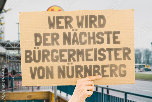 The phrase " Who's the next mayor of Nuremberg? " on a banner in men's hands blurred the background. Election. City management. Politics. Urban. Voter. Candidate