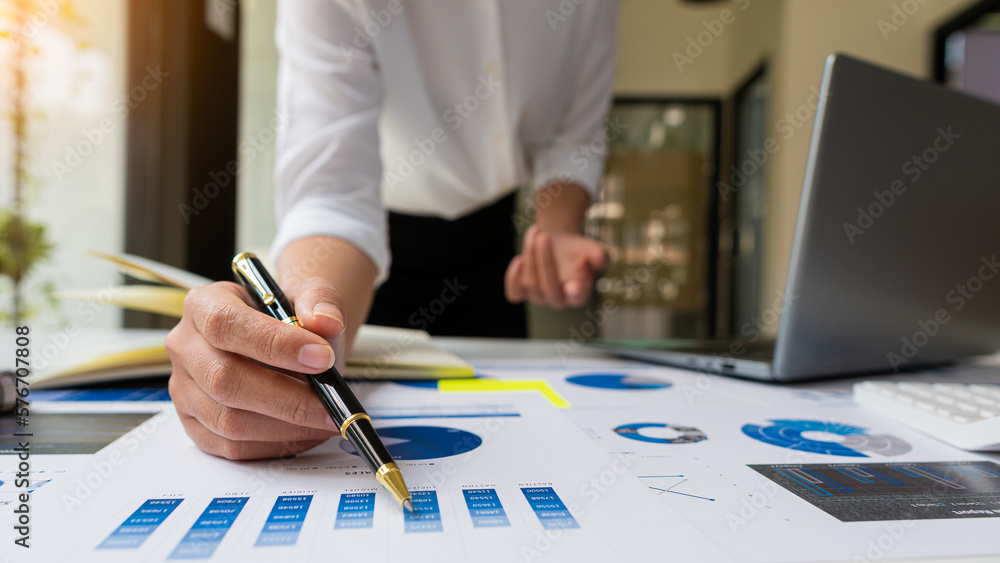 Asian ying businessman hand holding pen pointing at document. Financial graph. Plan. Marketing graph. Finance investment report and business strategy and working on laptop in office. Asian ying businessman hand holding pen pointing at document. Financial graph. Plan. Marketing graph. Finance investment report and business strategy and working on laptop in office.
