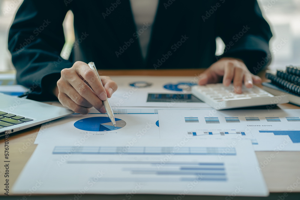 Asian ying businessman hand holding pen pointing at document. Financial graph. Plan. Marketing graph. Finance investment report and business strategy and working on laptop in office. Asian ying businessman hand holding pen pointing at document. Financial graph. Plan. Marketing graph. Finance investment report and business strategy and working on laptop in office.
