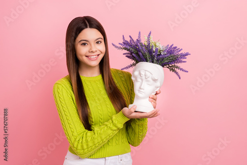 Photo of cheerful nice girl toothy smile arms hold vintage vase fresh flowers isolated on pink color background
