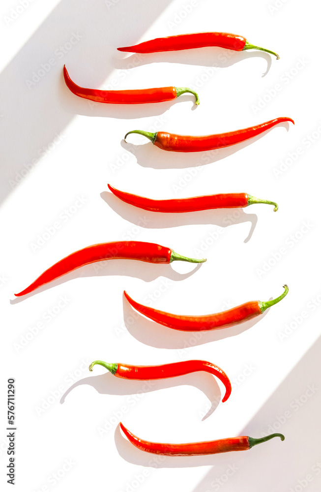 Creative composition made of red chilli peppers on white sunlit background with shadow. Healthy food ingredient concept. Flat lay. Top view Creative composition made of red chilli peppers on white sunlit background with shadow. Healthy food ingredient concept. Flat lay. Top view