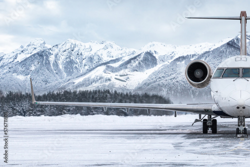 Front view of the luxury private jet on the winter airport apron on the background of high picturesque mountains
