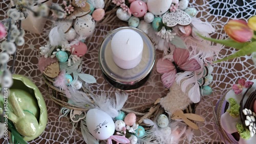 Beautiful festive served Easter table with decorations in dining room. Bunny, willow branches, tulips flowers, candle, colorful eggs, cake. Spring holiday setting. Family dinner. Selective focus