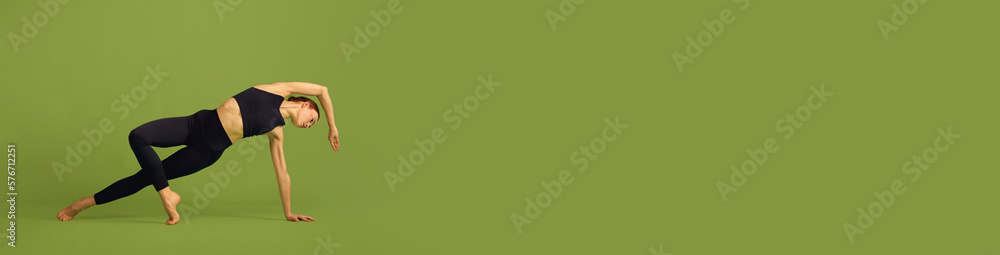Flexibility. Young girl with slim strong body training, doing stretching exercises on green studio background. Concept of sport, body care, beauty, fitness, active lifestyle. Banner. Copy space for ad Flexibility. Young girl with slim strong body training, doing stretching exercises on green studio background. Concept of sport, body care, beauty, fitness, active lifestyle. Banner. Copy space for ad