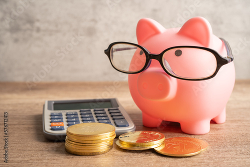 Pigging bank wearing eyeglass with coins and calculator; saving bank education concept. photo