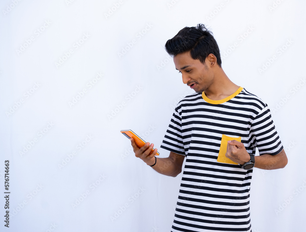 Young Boy Expressing Winning Gesture Looking at Mobile, Wearing Black and White Stripped T-shirt, Smiling face Young Boy Expressing Winning Gesture Looking at Mobile, Wearing Black and White Stripped T-shirt, Smiling face