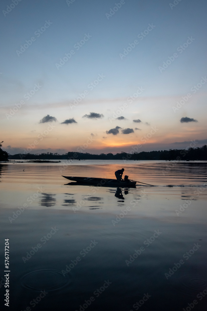 Fototapeta premium Fishermen row a wooden boat looking for fresh water fish in the river