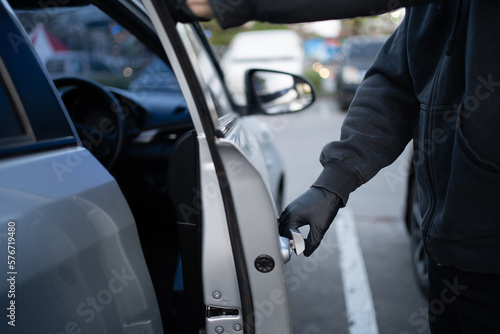 Close-up shot of a thief wearing a black shirt and black gloves. He tried to open the car door and tried to break in. car theft concept. © PBXStudio