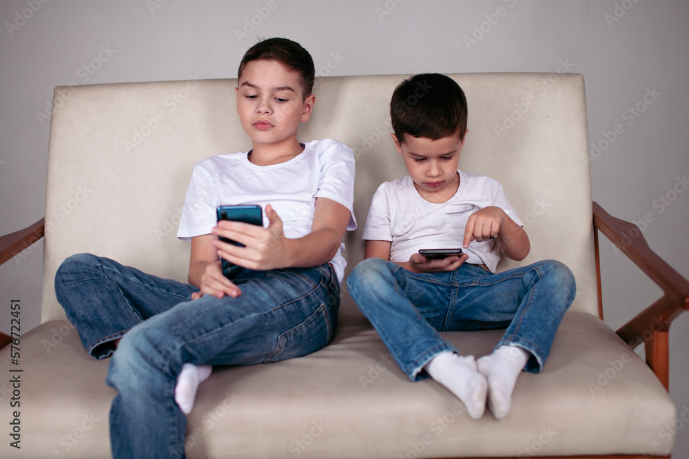 two brothers sitting on the sofa with phones two brothers sitting on the sofa with phones