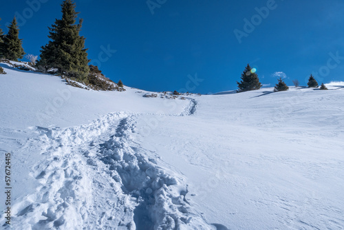 Path in deep snow to the top of a high mountain. Winter landscape high in the mountains, hiking trail as a symbol of overcoming obstacles. The trail goes along the ridge of the pass to the top of the 