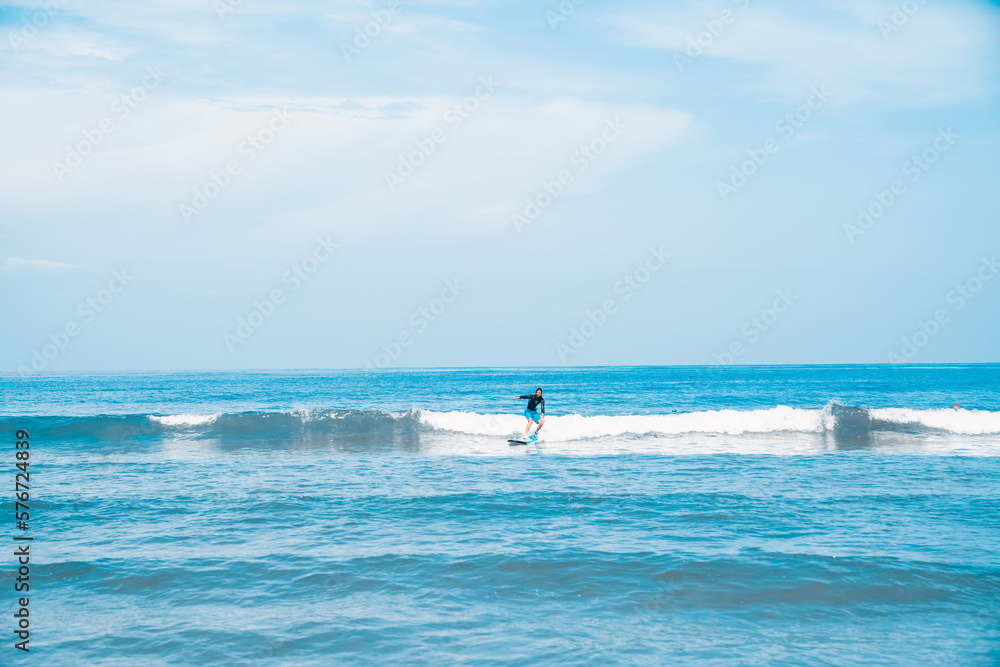 The man is surfing. A novice surfer on the waves in the ocean off the coast of Asia on the island of Bali in Indonesia.