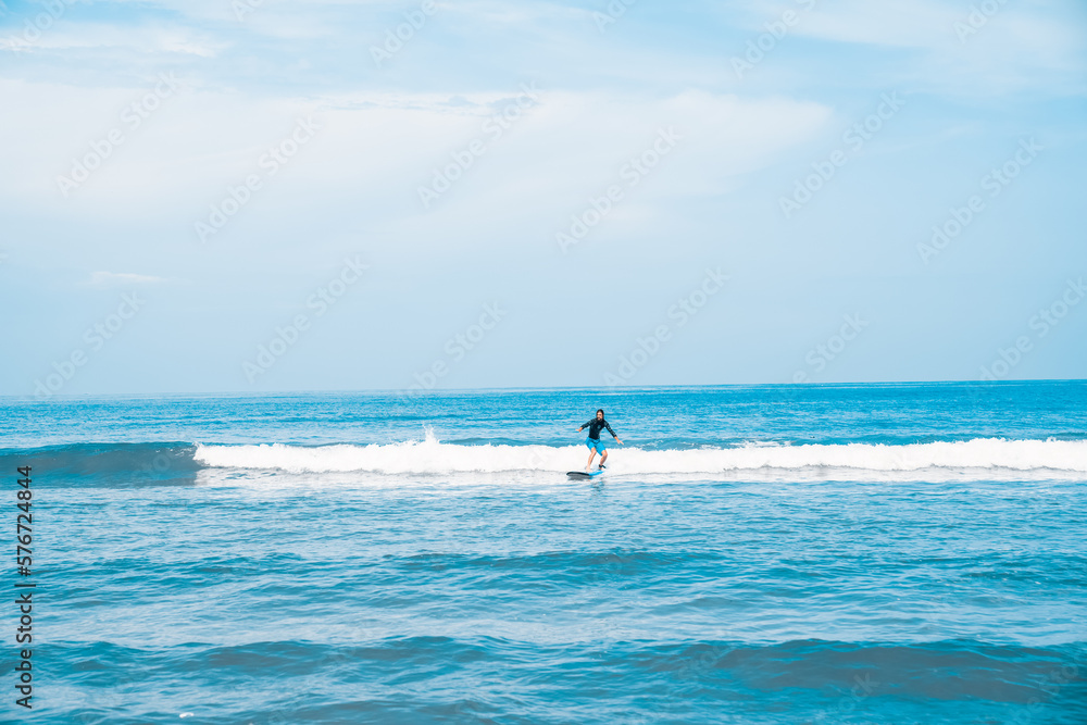 The man is surfing. A novice surfer on the waves in the ocean off the coast of Asia on the island of Bali in Indonesia.