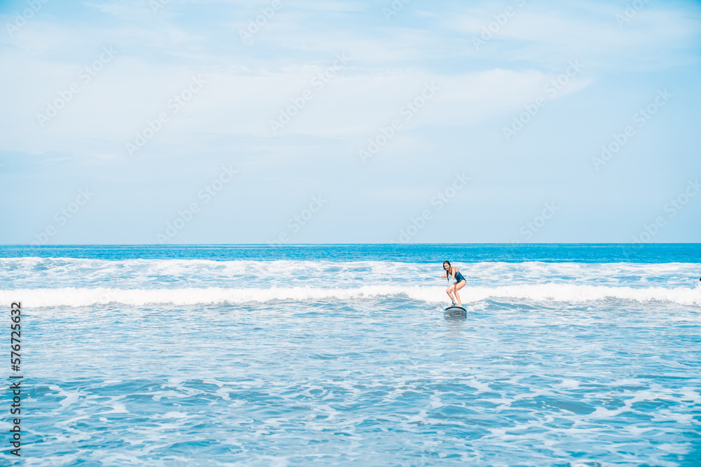 A woman is surfing. A surfer on the waves in the ocean off the coast of Asia on the island of Bali in Indonesia. Sports and extreme. Beauty and health. Fashion and beach style.