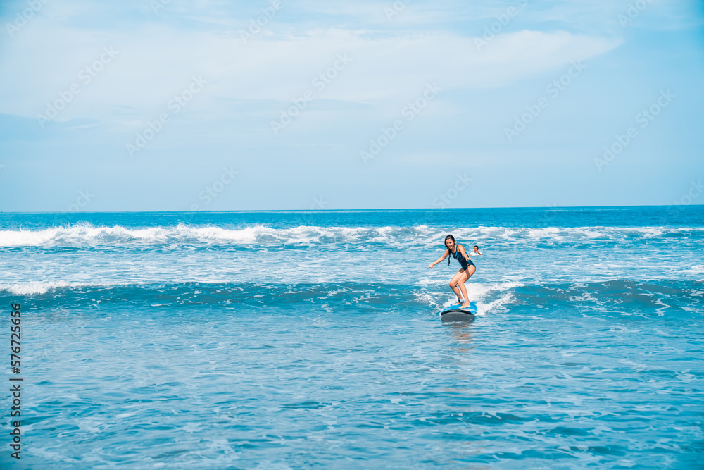 A woman is surfing. A surfer on the waves in the ocean off the coast of Asia on the island of Bali in Indonesia. Sports and extreme. Beauty and health. Fashion and beach style.