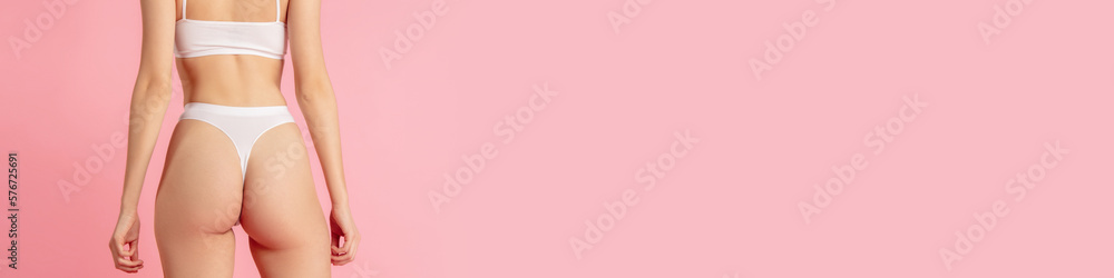 Cropped image of female body, buttocks in white cotton underwear over pink studio background. Anti-cellulite care. Body and skin care, fitness, natural beauty, health. Banner, flyer. Copy space for ad