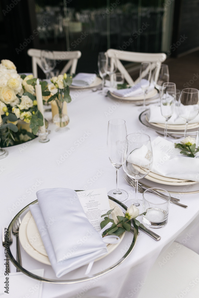 Served wedding table with decorative fresh white flowers and candles. Celebration details. Hanging flower beds and light bulbs Wedding decoration and decor, floristic concept
