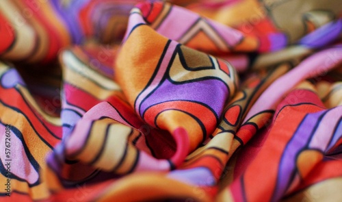 Close-up of a fabric with a bright abstract pattern: orange, purple, red, green. Selective focus, blur.