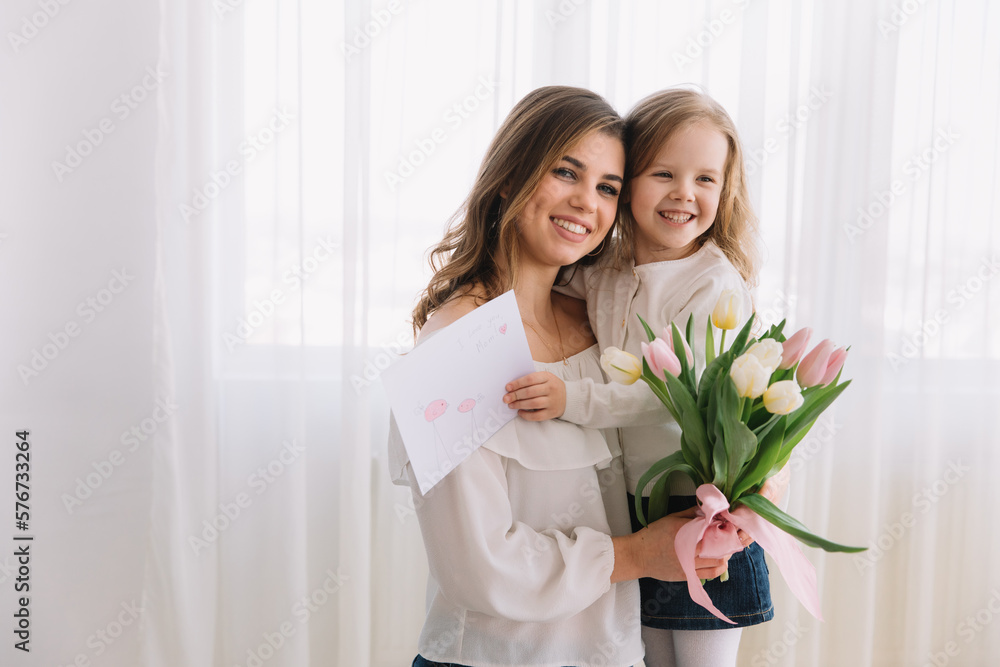 Happy mother's day. Child daughter congratulates moms and gives her a postcard and flowers tulips. Happy mother's day. Child daughter congratulates moms and gives her a postcard and flowers tulips.