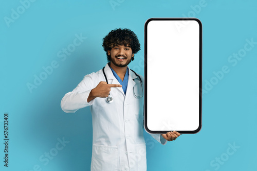 Handsome eastern man doctor hodling big smartphone, mockup photo