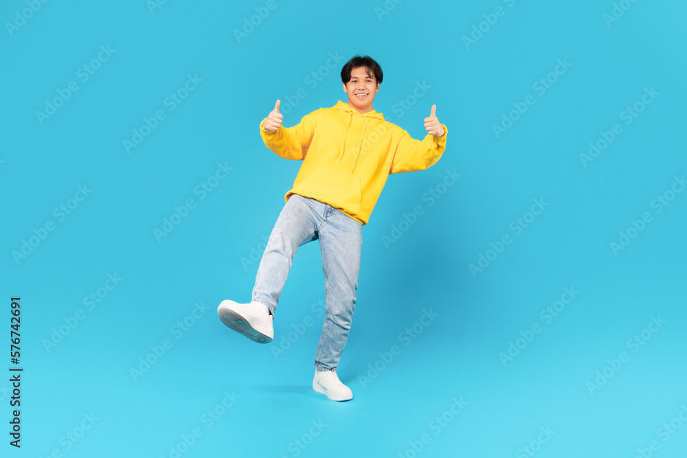 Fototapeta premium Asian Male Teen Gesturing Thumbs Up With Both Hands, Studio