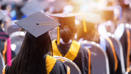 Rear view of university graduates wearing graduation gown and cap in the commencement day