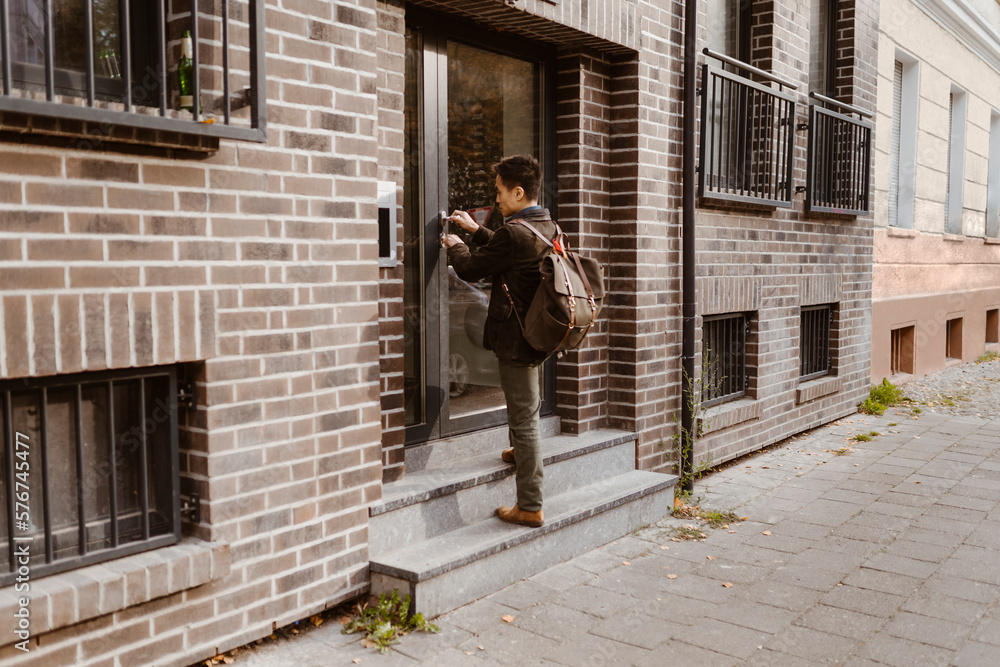 Man standing on steps while locking door of apartment Man standing on steps while locking door of apartment