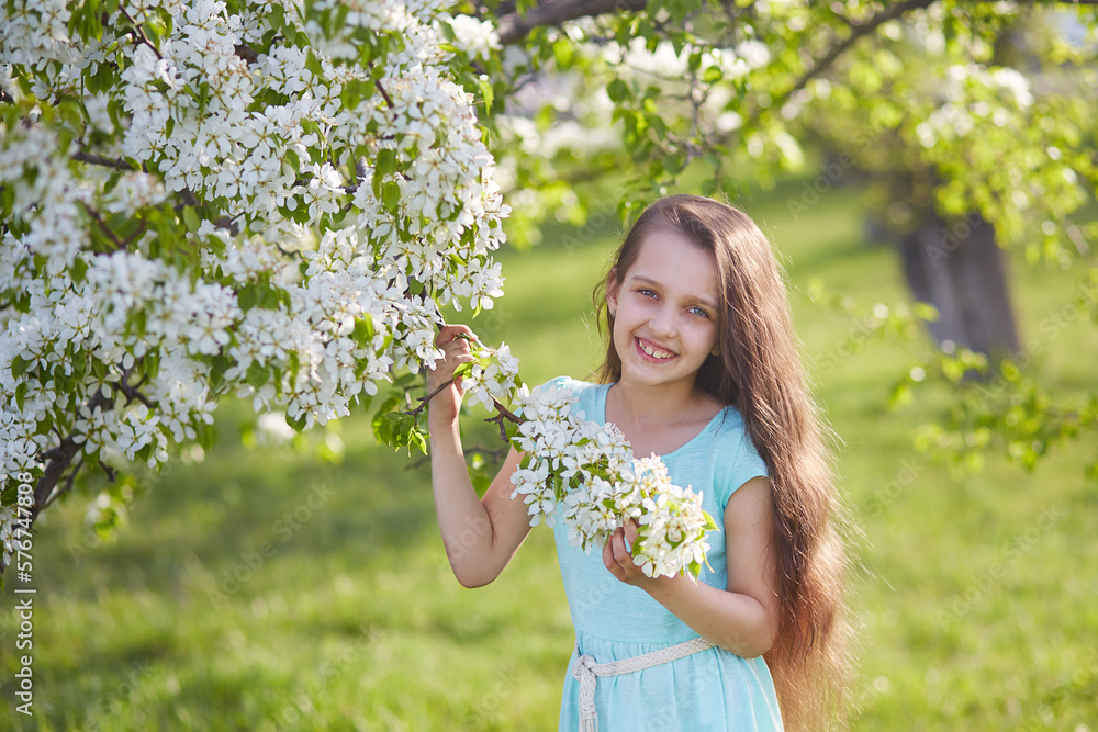 A smiling young girl in a blooming apple orchard. Beautiful spring background. A smiling young girl in a blooming apple orchard. Beautiful spring background.