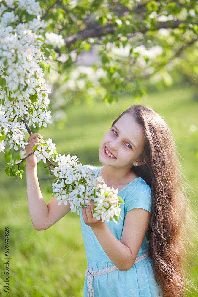 A young girl with loose long hair in a blooming apple orchard. Vertical orientation A young girl with loose long hair in a blooming apple orchard. Vertical orientation