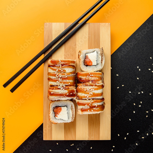 Photo of sushi on a bright background. Top view of sushi and rolls. Traditional Japanese cuisine. Delicious rolls on the board up close. Sesame seeds on the background. California, Philadelphia
