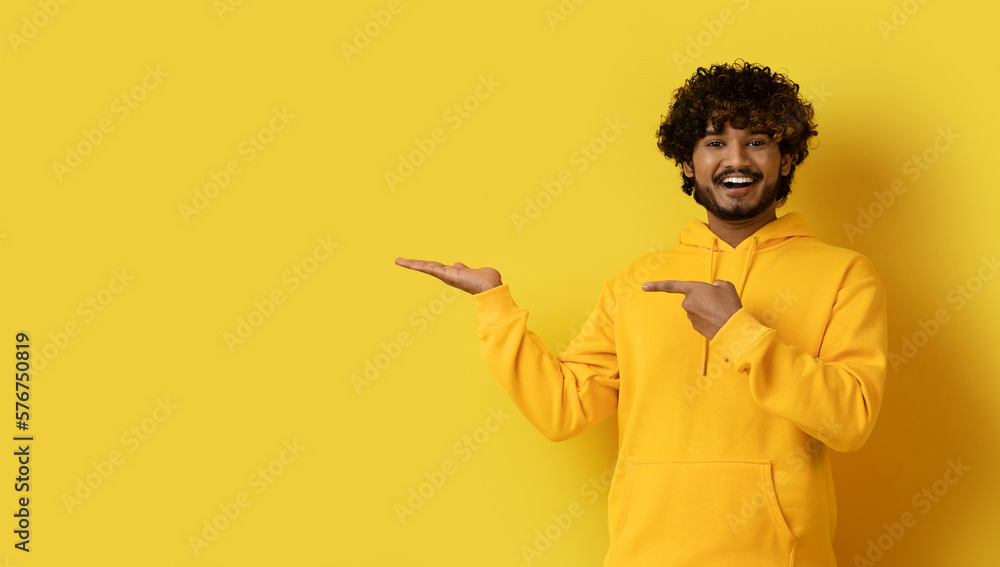 Positive cool eastern guy hipster showing something on his palm Positive cool eastern guy hipster showing something on his palm