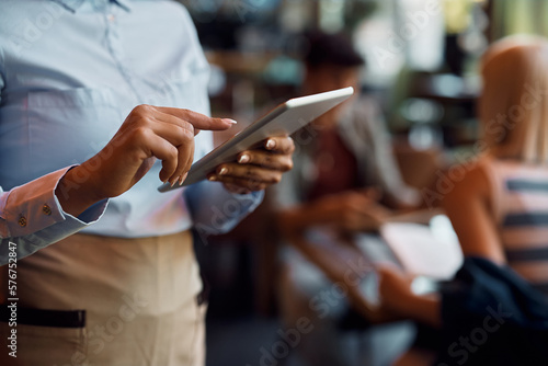Close up of black waitress using digital tablet while working in cafe.
