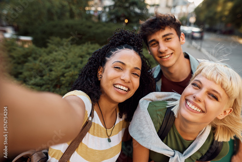 Group of cheerful college friends taking selfie and looking at camera.