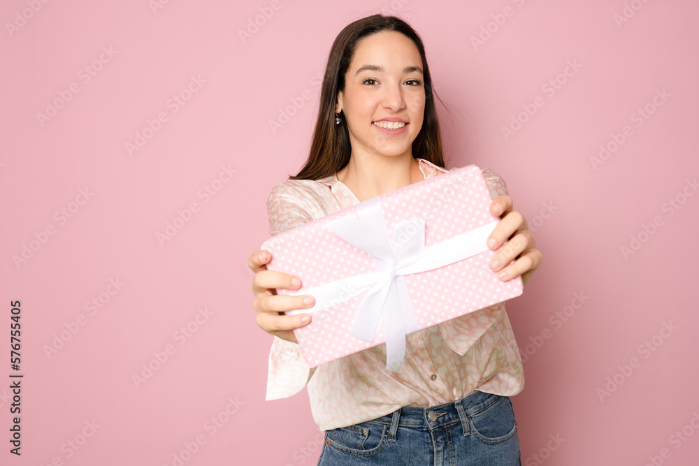 Close-up portrait of happy exited pretty brunette woman holding gift box, looking at camera, isolated on pink background Close-up portrait of happy exited pretty brunette woman holding gift box, looking at camera, isolated on pink background