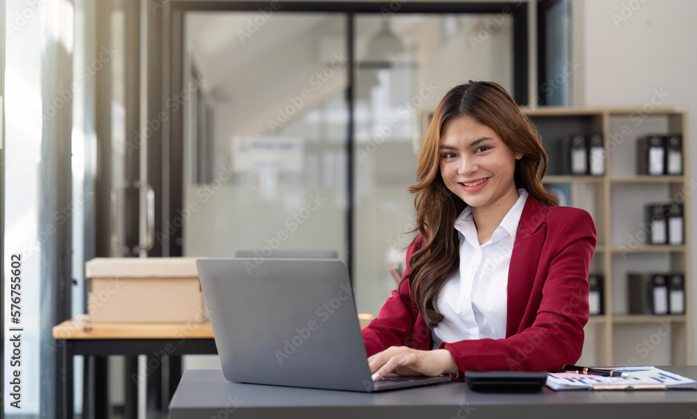 Asian Business woman using laptop and calculator for doing math finance on an office desk, tax, report, accounting, statistics, and analytical research concept Asian Business woman using laptop and calculator for doing math finance on an office desk, tax, report, accounting, statistics, and analytical research concept