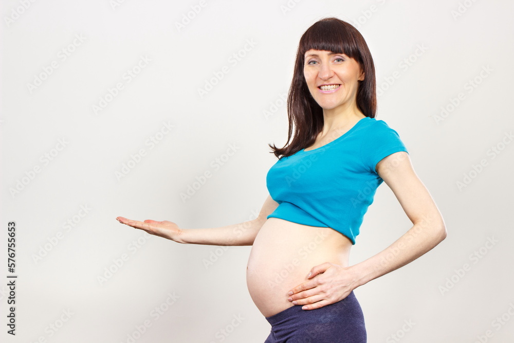 Happy woman in pregnant showing empty hand for text or different products. Expecting for newborn. Extending family Happy woman in pregnant showing empty hand for text or different products. Expecting for newborn. Extending family