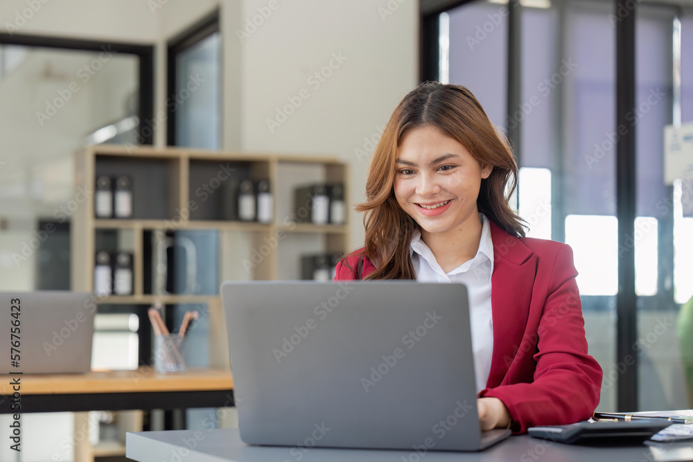 Asian Business woman using laptop and calculator for doing math finance on an office desk, tax, report, accounting, statistics, and analytical research concept Asian Business woman using laptop and calculator for doing math finance on an office desk, tax, report, accounting, statistics, and analytical research concept