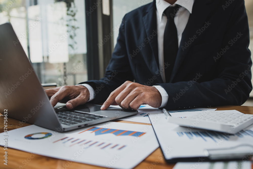 Businessman hands working on laptop computer with market report document and management business project, Business accounting concept. Businessman hands working on laptop computer with market report document and management business project, Business accounting concept.