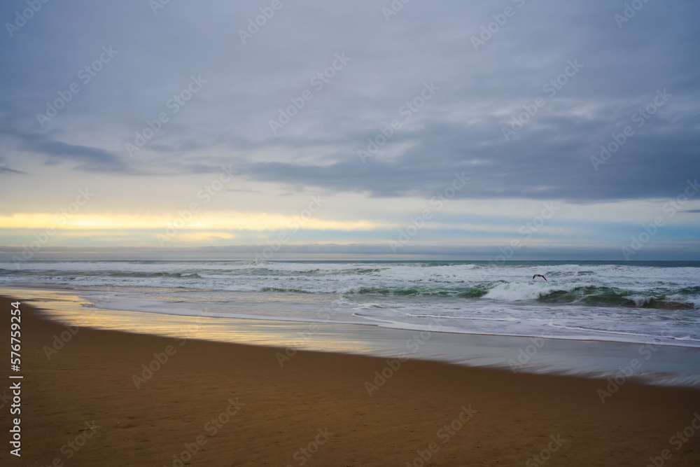 Dramatic sunset on the beach. Wide sandy beach, stormy sea, and beautiful cloudy sky, copy space