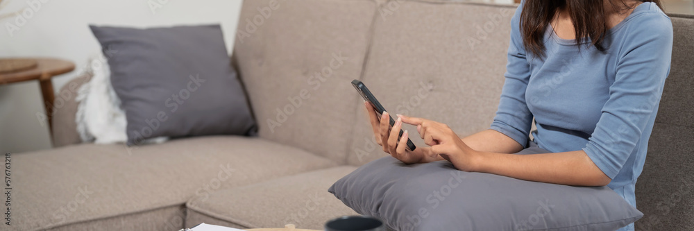Happy asian woman using mobile phone and receiving good news.on sofa at living room.