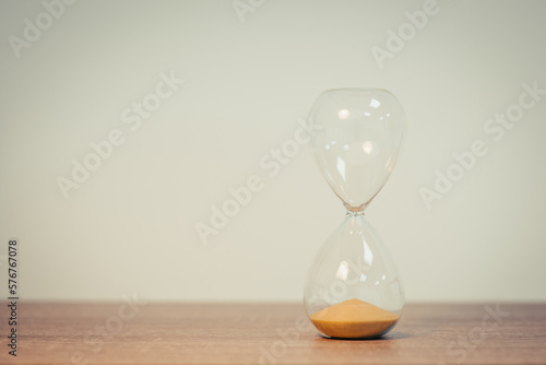 Hourglass on wooden table, isolated on the white background, close up, copy space. Sandglass, sand timer, concept of passing time, deadline, toned image